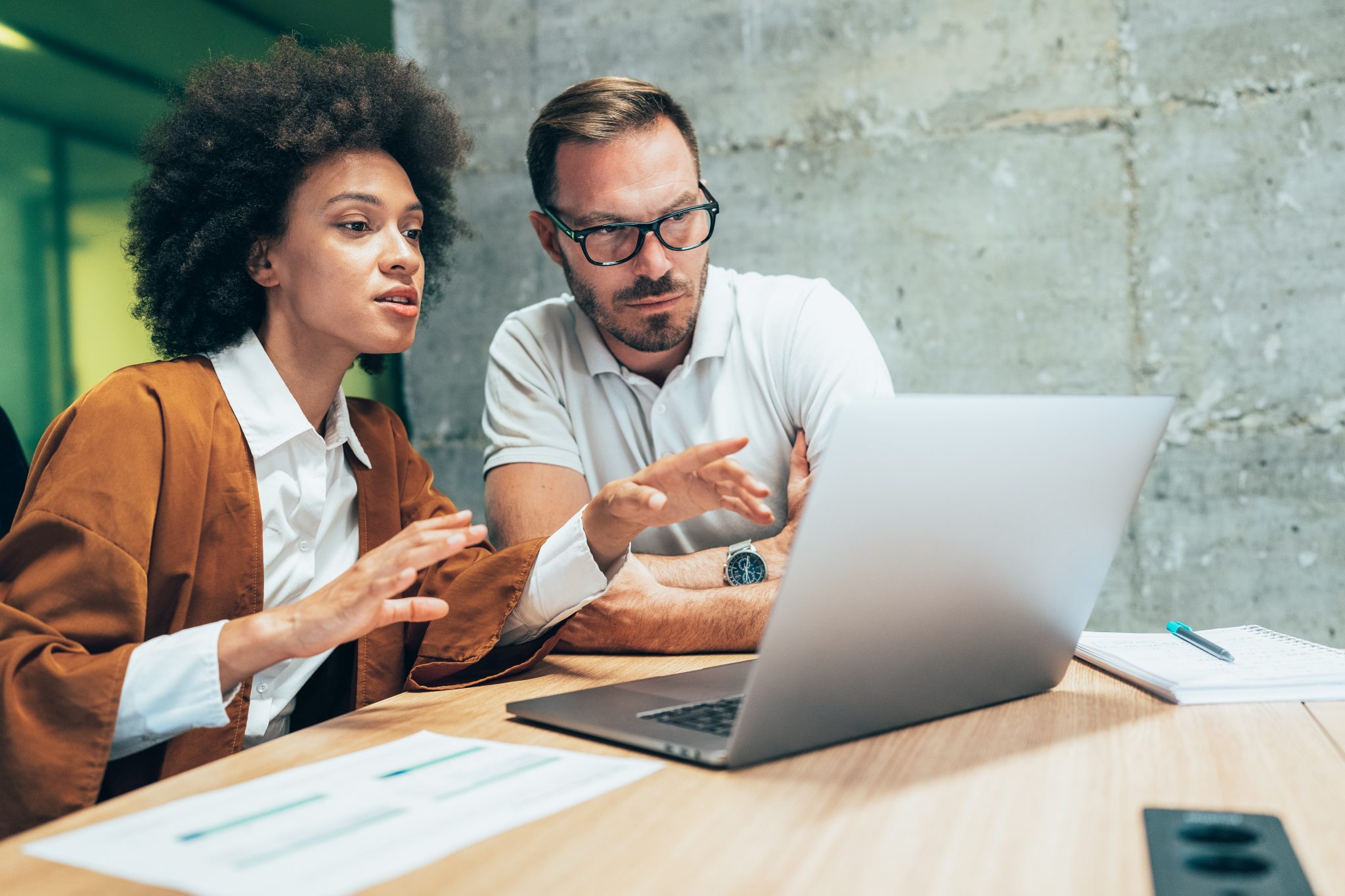 Two people viewing reports on a laptop.